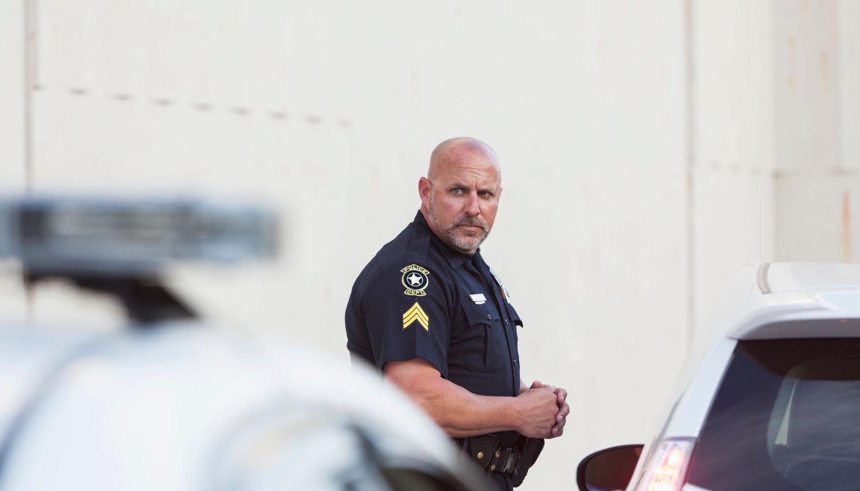 Serious police officer standing next to car