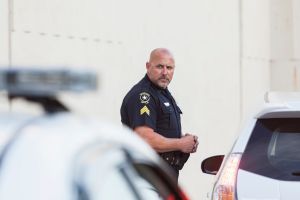 Serious police officer standing next to car