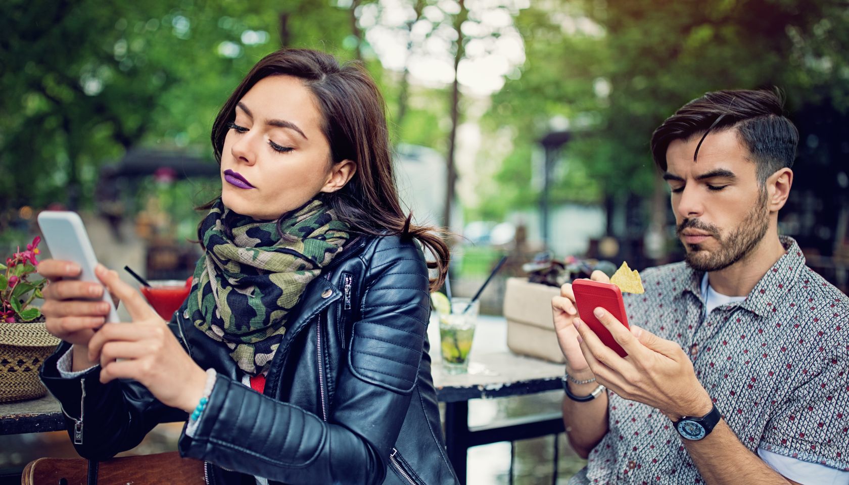 Couple is looking in their mobile phones and sulking each other in the cafe