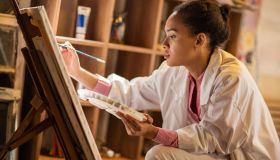 Young African American painter working in her studio.