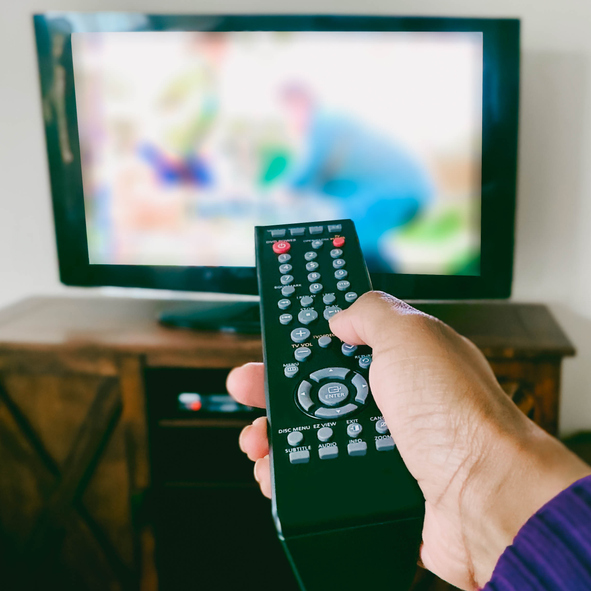 Close-Up of Woman's Hand Pointing Remote Control at TV