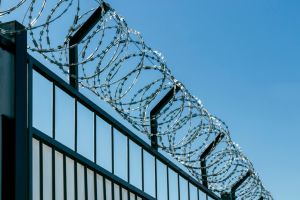 Barbed wire on an iron fence. Against the background of the blue sky