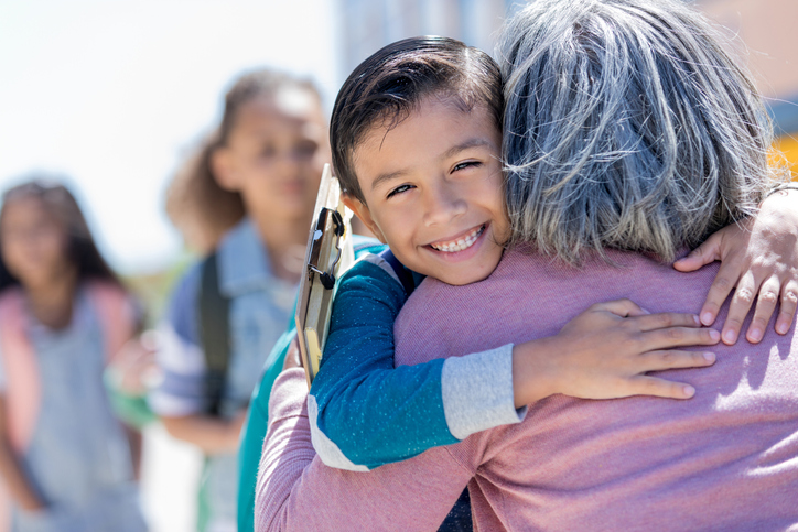 Hispanic boy hugs grandmother before school