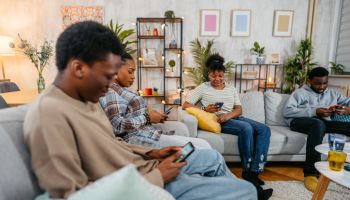 Black Family Using Their Phones In The Living Room