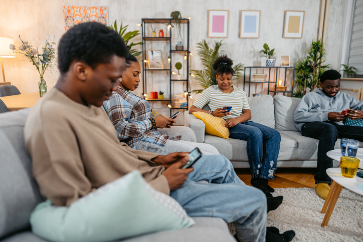 Black Family Using Their Phones In The Living Room