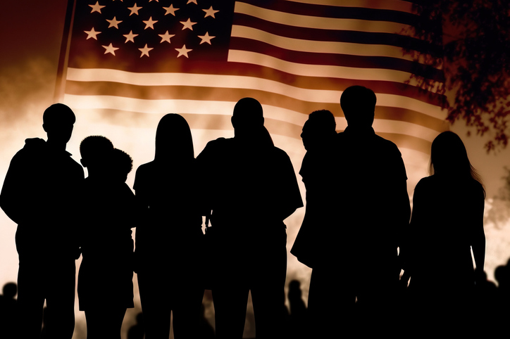 Black silhouette of a large family looking at a huge United States flag waving in the sky. July 4th, Independence Day