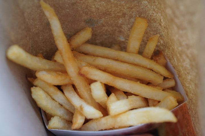 Hand grabbing french fries from a paper bag
