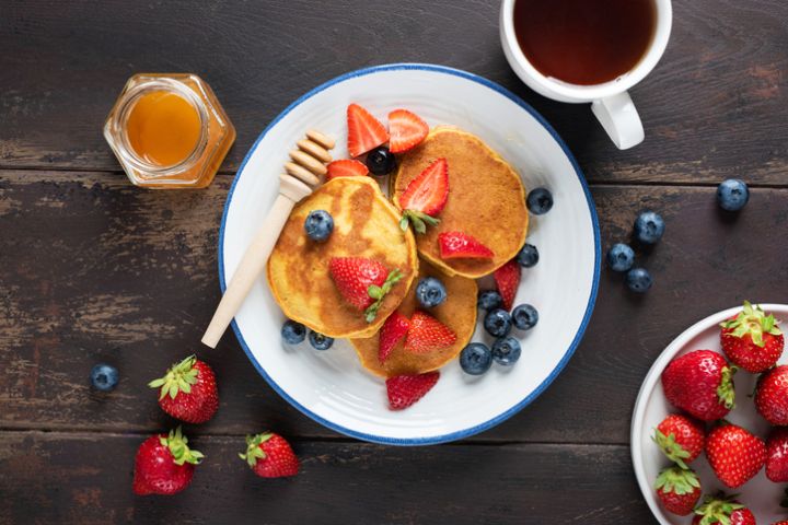 Pancakes with honey and berries and cup of tea
