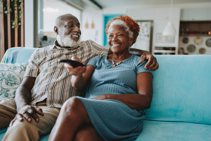 Portrait senior couple watching TV in living room