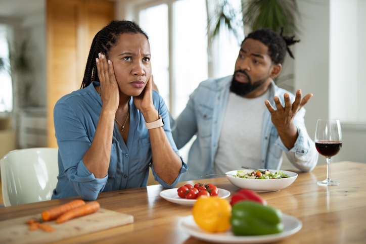 Frustrated African American couple arguing during lunch at home.