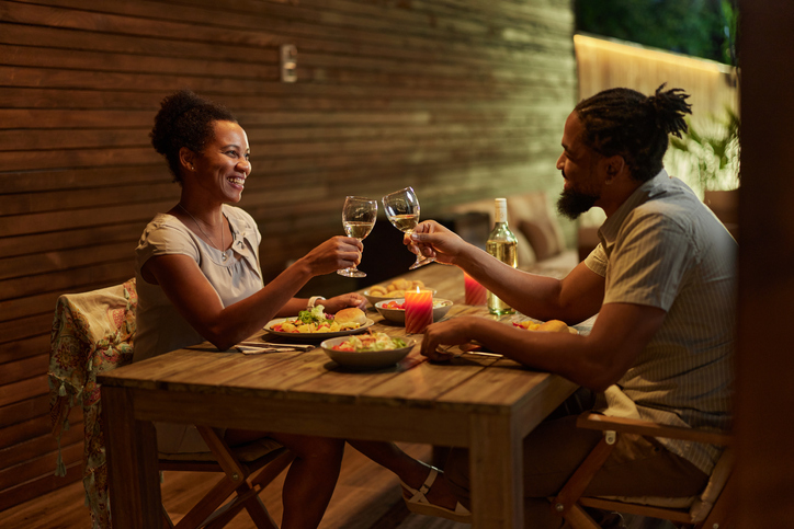 Happy black couple toasting during dinner on a patio.