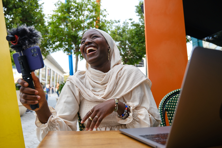 Muslim woman laughing recording a online streaming in a cafeteria