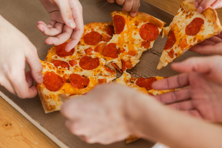 Home party. Top view male female hands taking slices of pizza from food delivery open box. Group of hungry friends sharing delicious lunch eating ordered pepperoni pizza. Food pizza delivery.