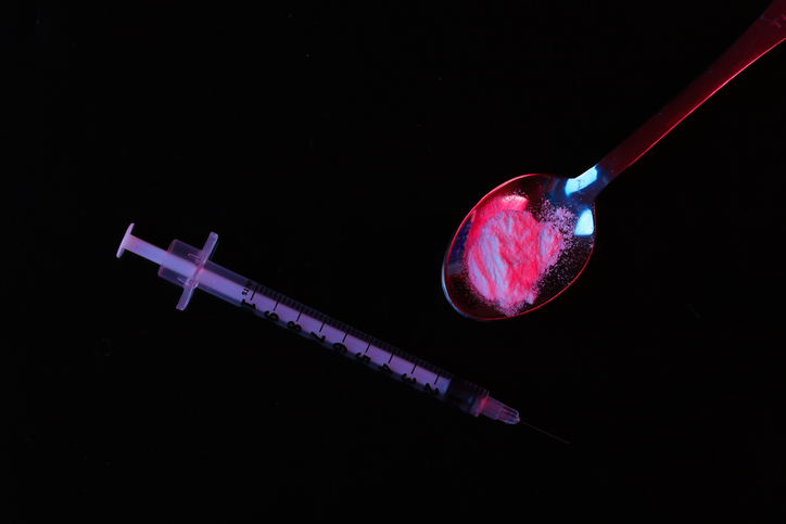 Syringes and heroin powder on black background with red blue neon light. Addict concept