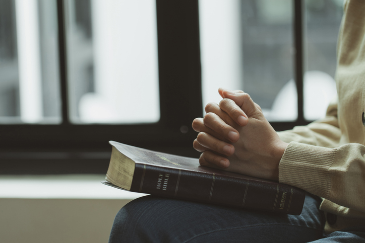 Praying woman folding hands over bible with light from the window.represents faith and spirituality in everyday life. Pray to God .religion. Christian life crisis prayer to god. believe in goodness.
