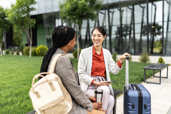 Two diversity business women sitting in front of airport and talking