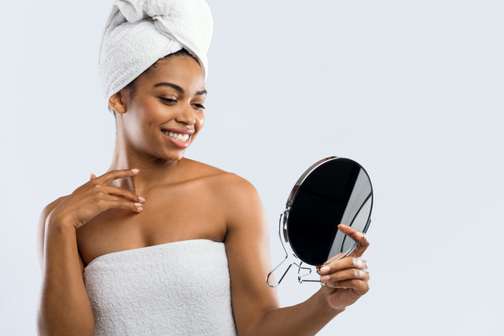 Pretty girl checking her skin in mirror after shower