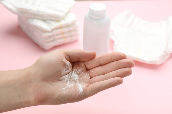 Woman with dusting powder on pink background, closeup