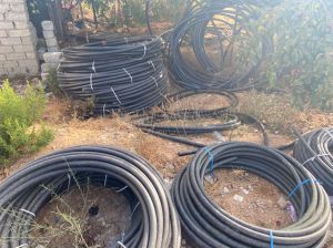 Many large coils of black plastic thick large diameter hoses for pumping liquids in an industrial warehouse