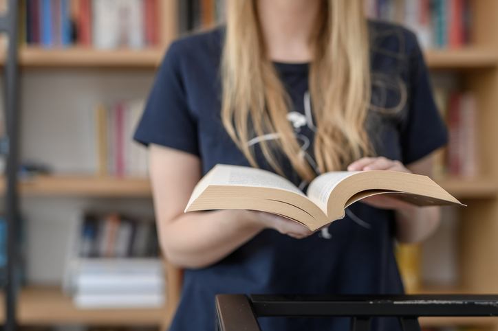 A young girl reading a paper book in a public library