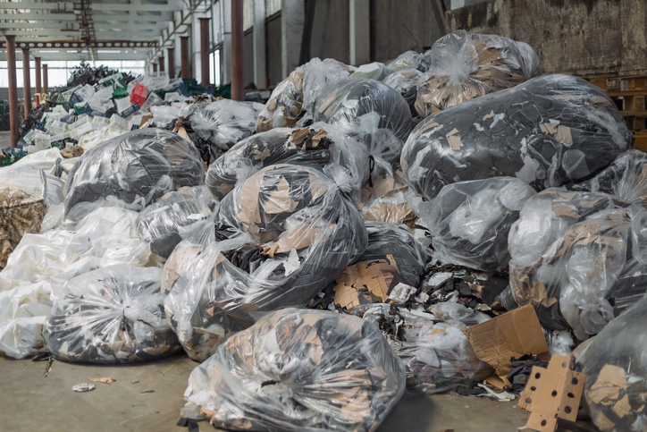 Large pile of garbage bags and loose trash polluting a warehouse