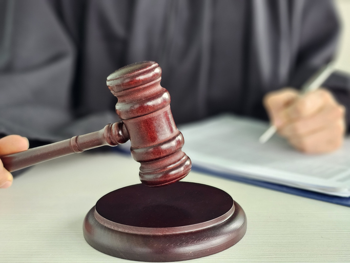 Judge presiding over court session while preparing official documentation with gavel in hand during legal proceedings concept