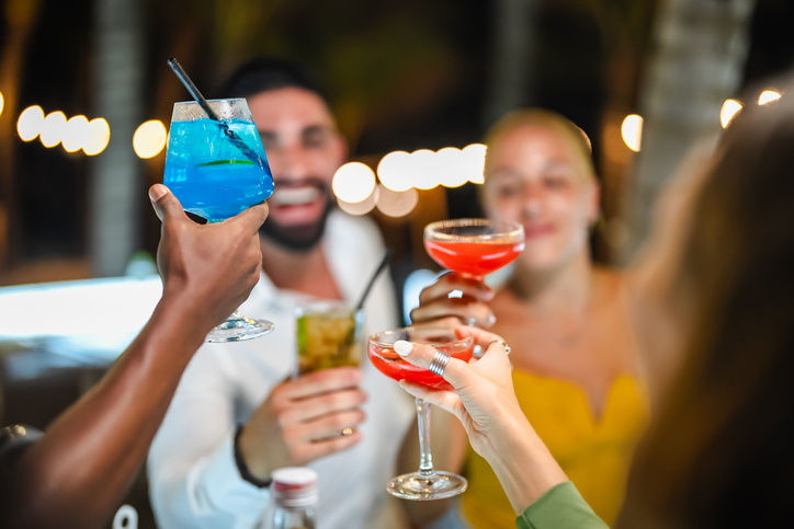 Group of friends toasting with colorful cocktails during a lively night out, showcasing vibrant drinks and festive vibes