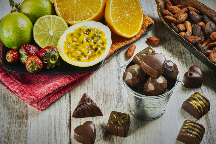 Top view of assortment of chocolate sweets and fruits on rustic wooden table.
