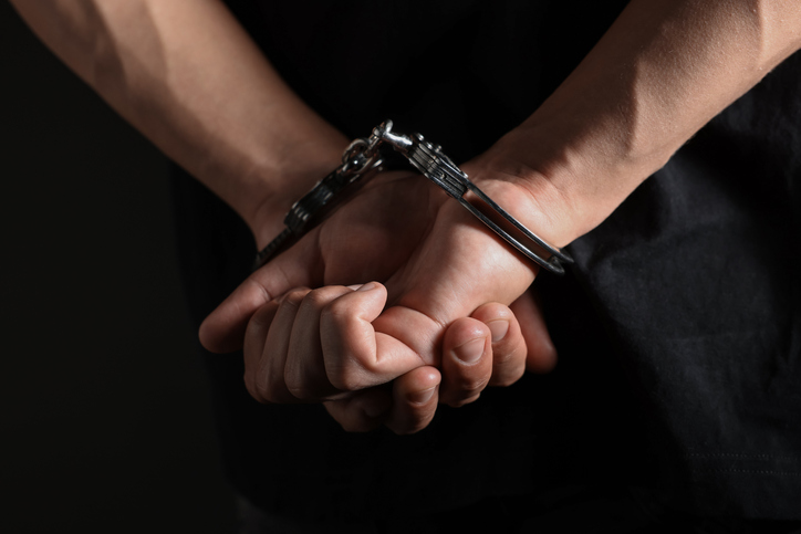 Man in metal handcuffs on black background, closeup