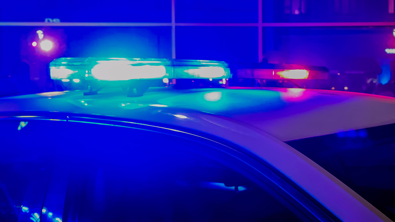 Blue, red light on top of a police vehicle on city street at night