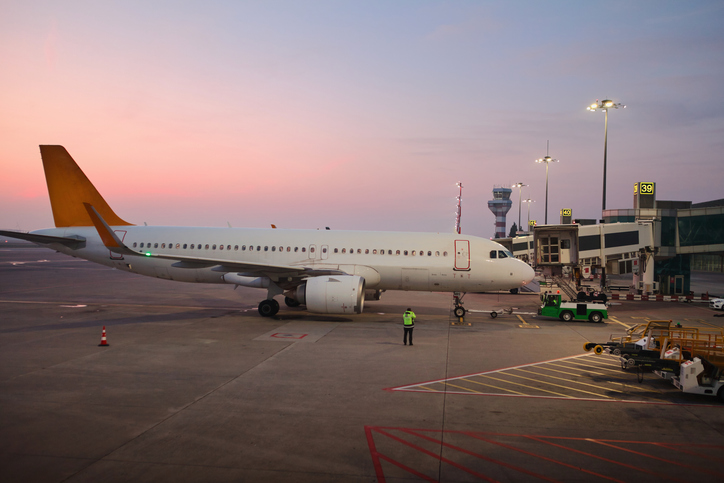 The aircraft docked at the airport terminal at sunset.