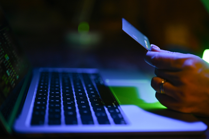 Hand holding credit card making online payment on laptop
