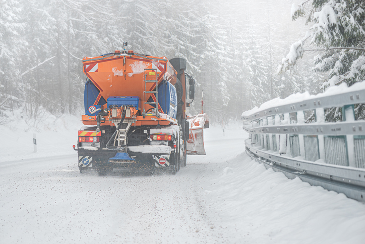 Snow plow sprinkling snowy road after snowstorm.
