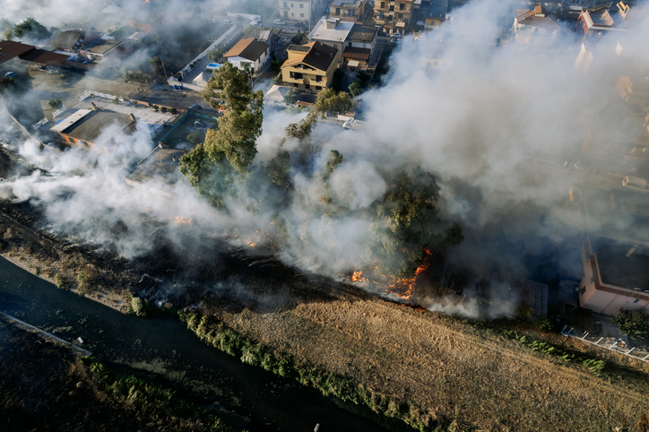 Aerial drone view of wildfire near houses and trees