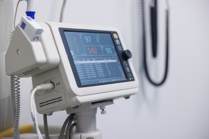 Vital signs monitor displaying patient data in a hospital room. Medical technology for tracking heart rate, blood pressure, and oxygen saturation.