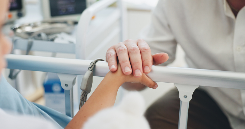 Father, visit and holding hands with kid in hospital bed for support, reassurance and medical recovery. Person, comfort and child for treatment, family empathy and encouragement of healthcare surgery
