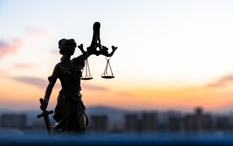 Legal law concept statue of Lady Justice with scales of justice against sunset sky and city background