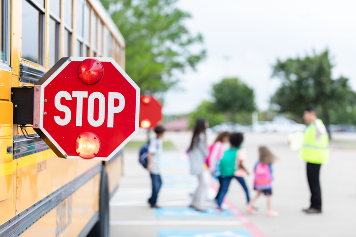 School bus stop sign aids children crossing busy street during dismissal