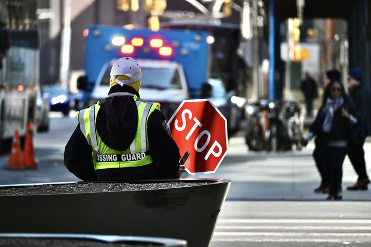 New York City Crossing Guard Holds a Stop Sign and Stands Ready to Help