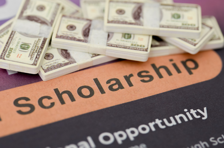 Stack of Hundred Dollar Bills on Scholarship Application Form for Education Funding