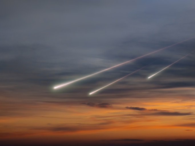Meteors in the sky at sunset. Fireballs with trails above the clouds.