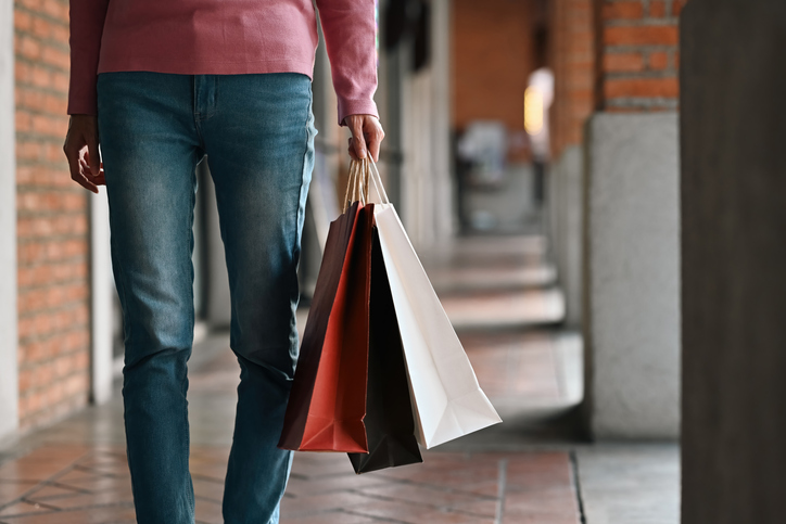 Close-up view of a person walking with shopping bags in hand along a stylish city walkway