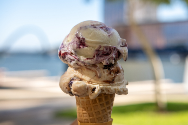 Hand holding Blueberry and Chocolate Gelato, Ice-cream with waffle cone, on blurred background of the lake.