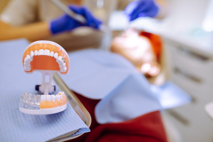 Close Up High Angle View of Dentist Cleaning Patient Teeth With Dental Tools and Protective Equipment in Modern Sterile Dental Clinic Interior