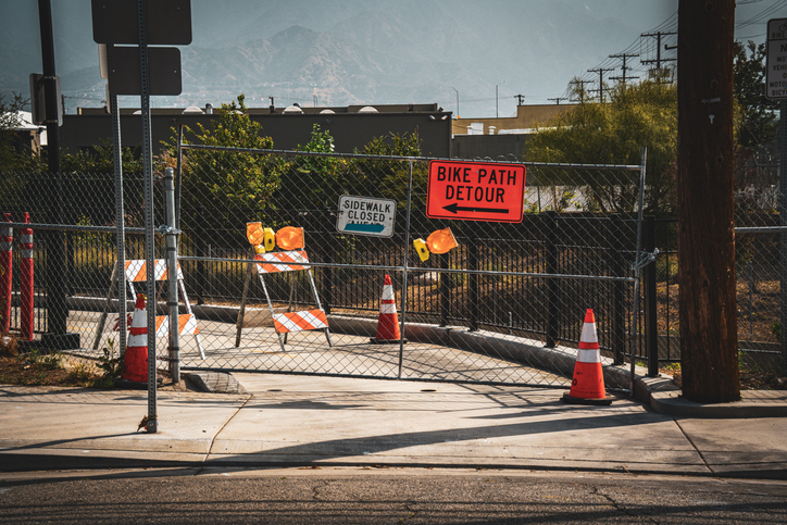 Temporary bike path detour signs and construction barriers block the way