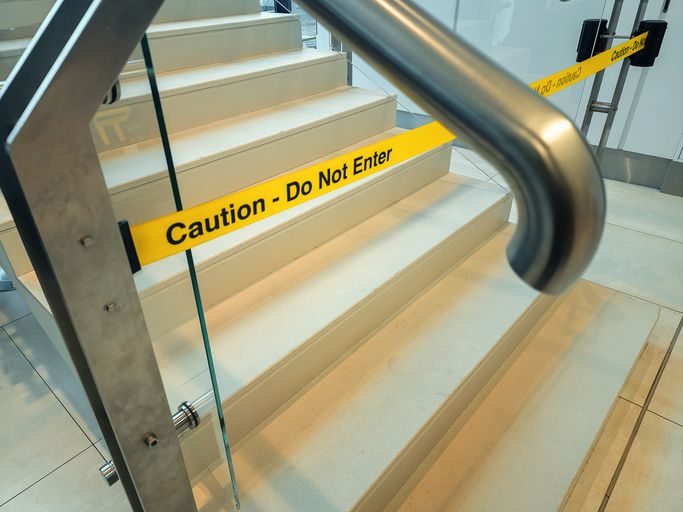 Caution tape restricting access to an indoor staircase