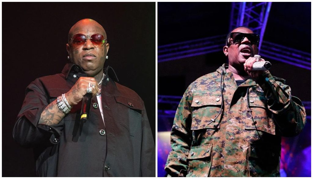 Two musicians performing on stage, one wearing a red jacket and sunglasses, the other in camouflage military-style clothing.
