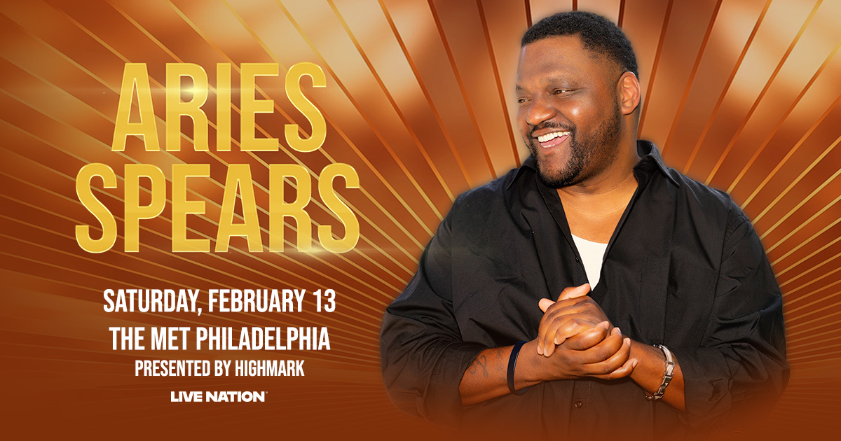 A smiling Black man wearing a black jacket stands in front of a large orange and yellow background with the text "ARIES SPEARS" and event details.